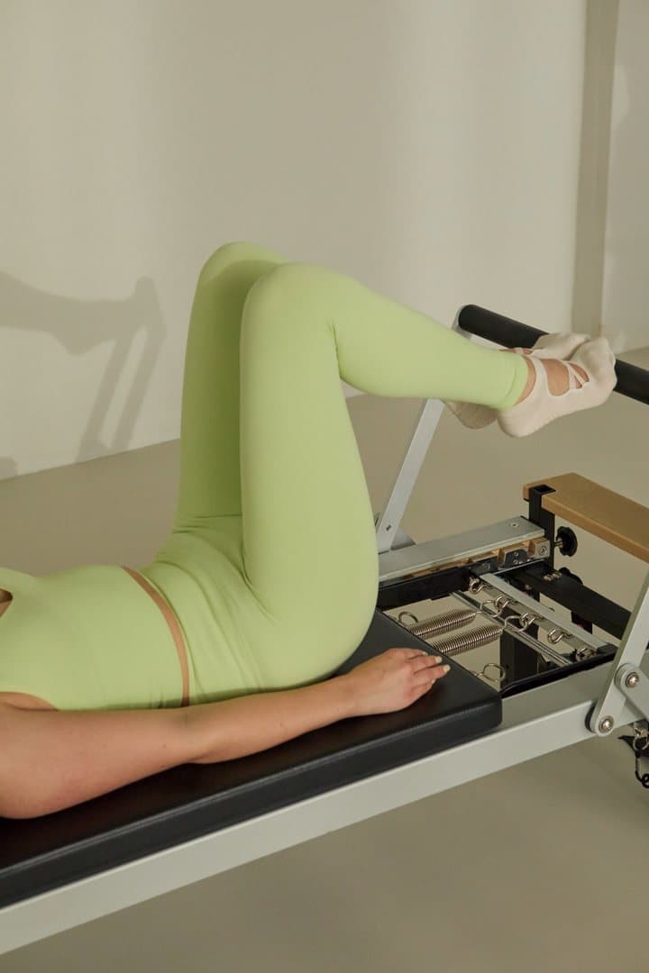 A client wearing green on a Reformer
